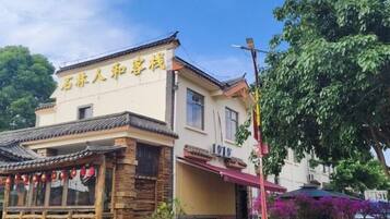 A traditional building with a sign in a foreign language, a covered outdoor seating area, and a tree in the background.