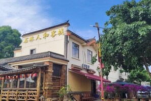 A traditional building with a sign in a foreign language, a covered outdoor seating area, and a tree in the background. - Tiandi Renhe Inn (Shilin)