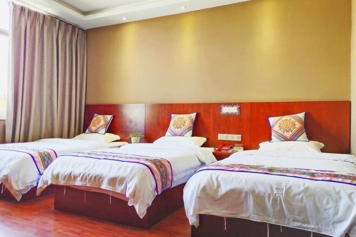 A hotel room with two beds, wooden headboards, and a large window with curtains.