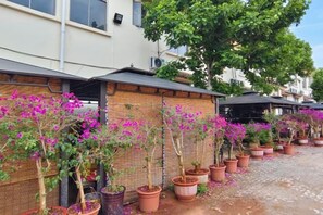 A row of potted plants with pink flowers along a brick wall. - Tiandi Renhe Inn (Shilin)