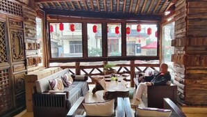 A traditional wooden interior with a sofa set, a table, and a view through large windows. - Tiandi Renhe Inn (Shilin)