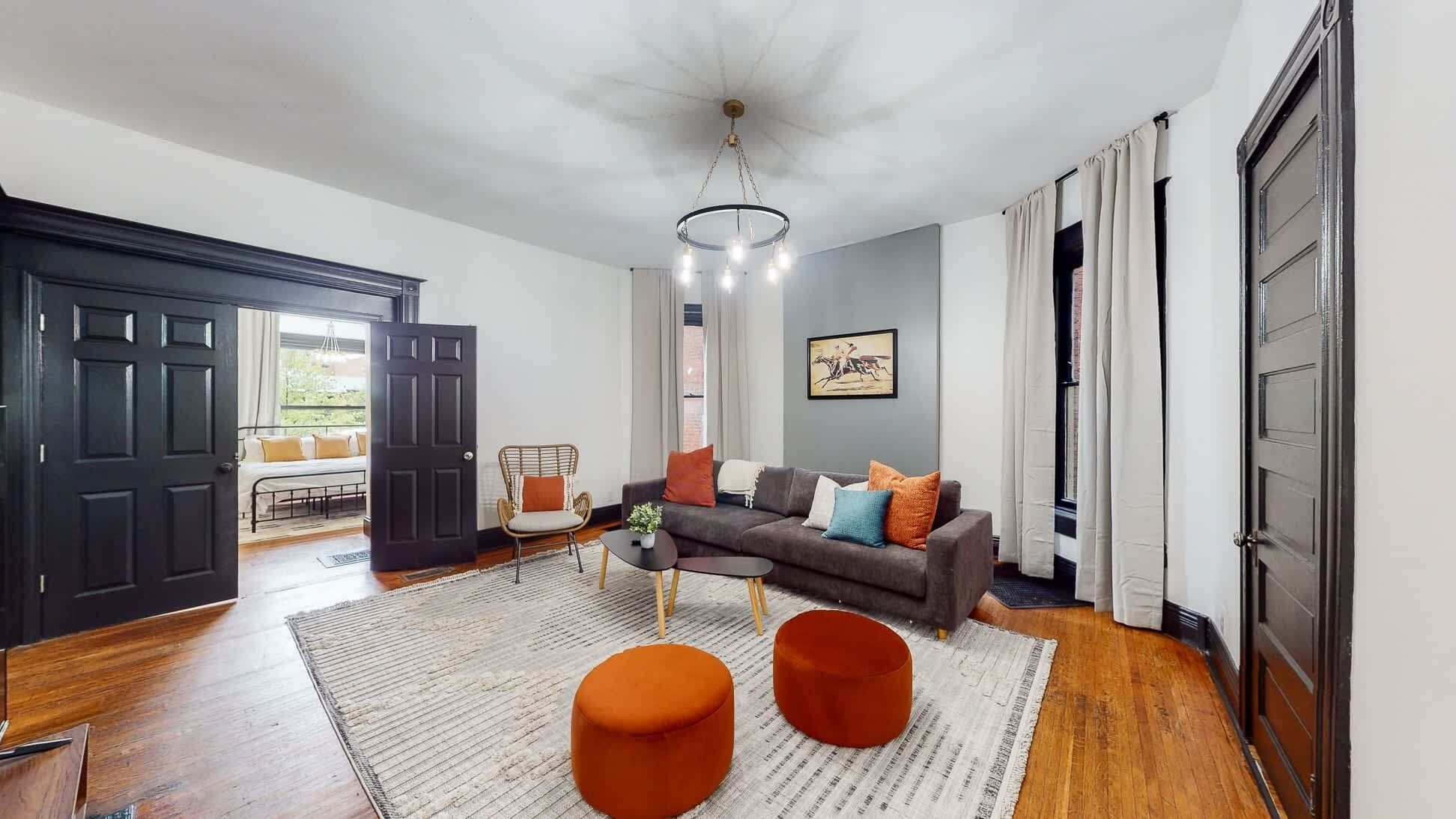 A living room with a sofa, ottomans, a coffee table, and a chandelier.