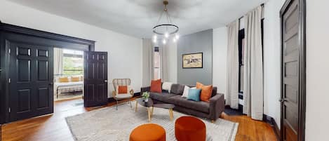 A living room with a sofa, ottomans, a coffee table, and a chandelier.