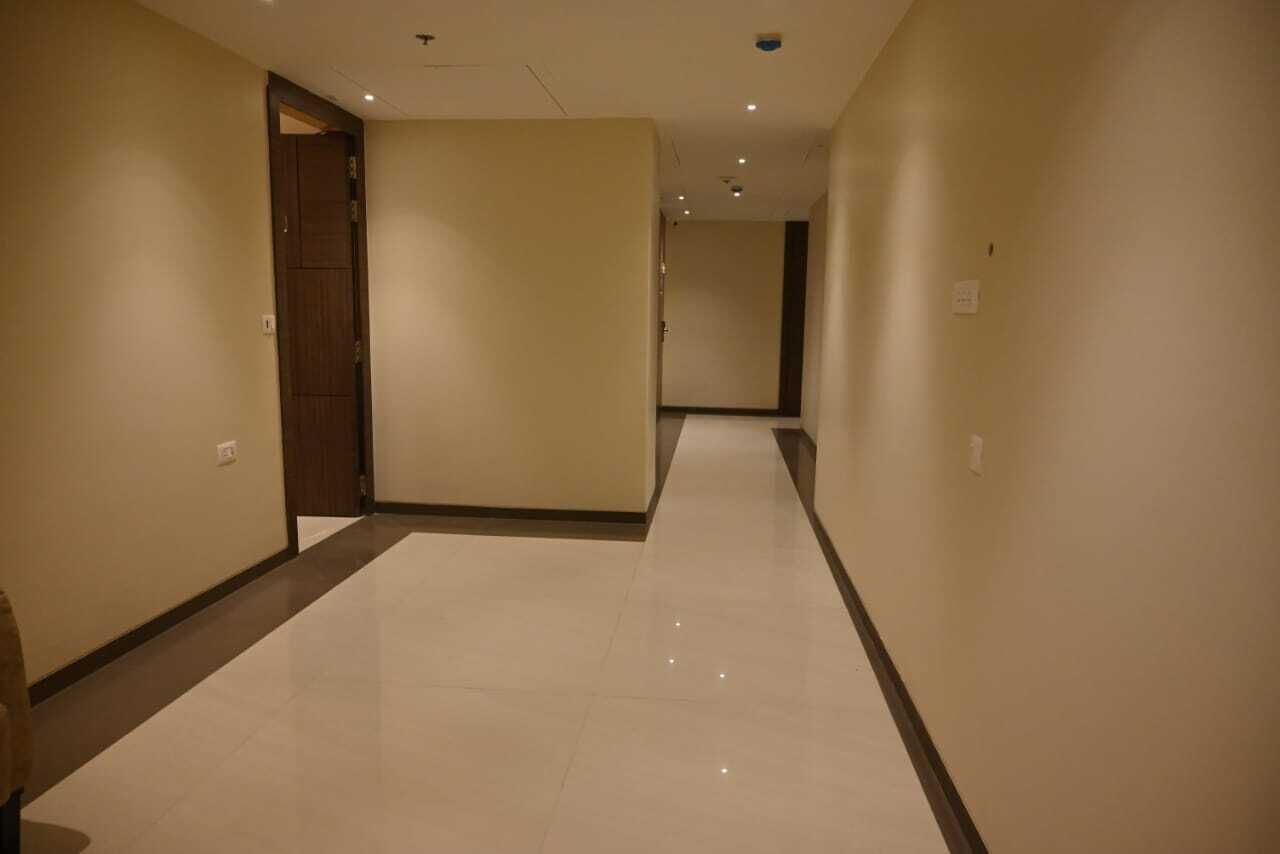 A long, narrow hallway with a polished floor and beige walls.