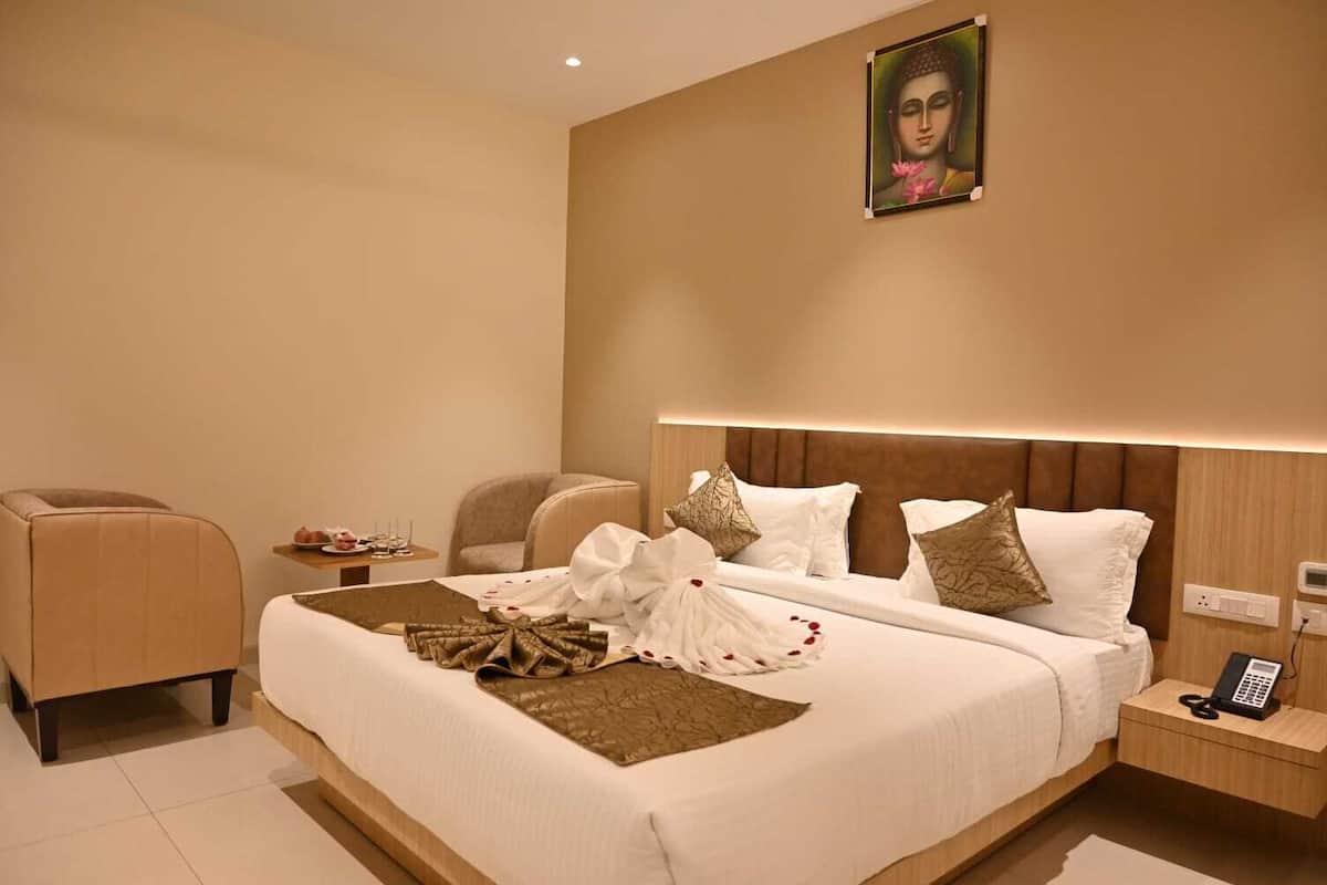 A modern hotel room with a large bed, a bedside table with a phone, and a wall-mounted painting.