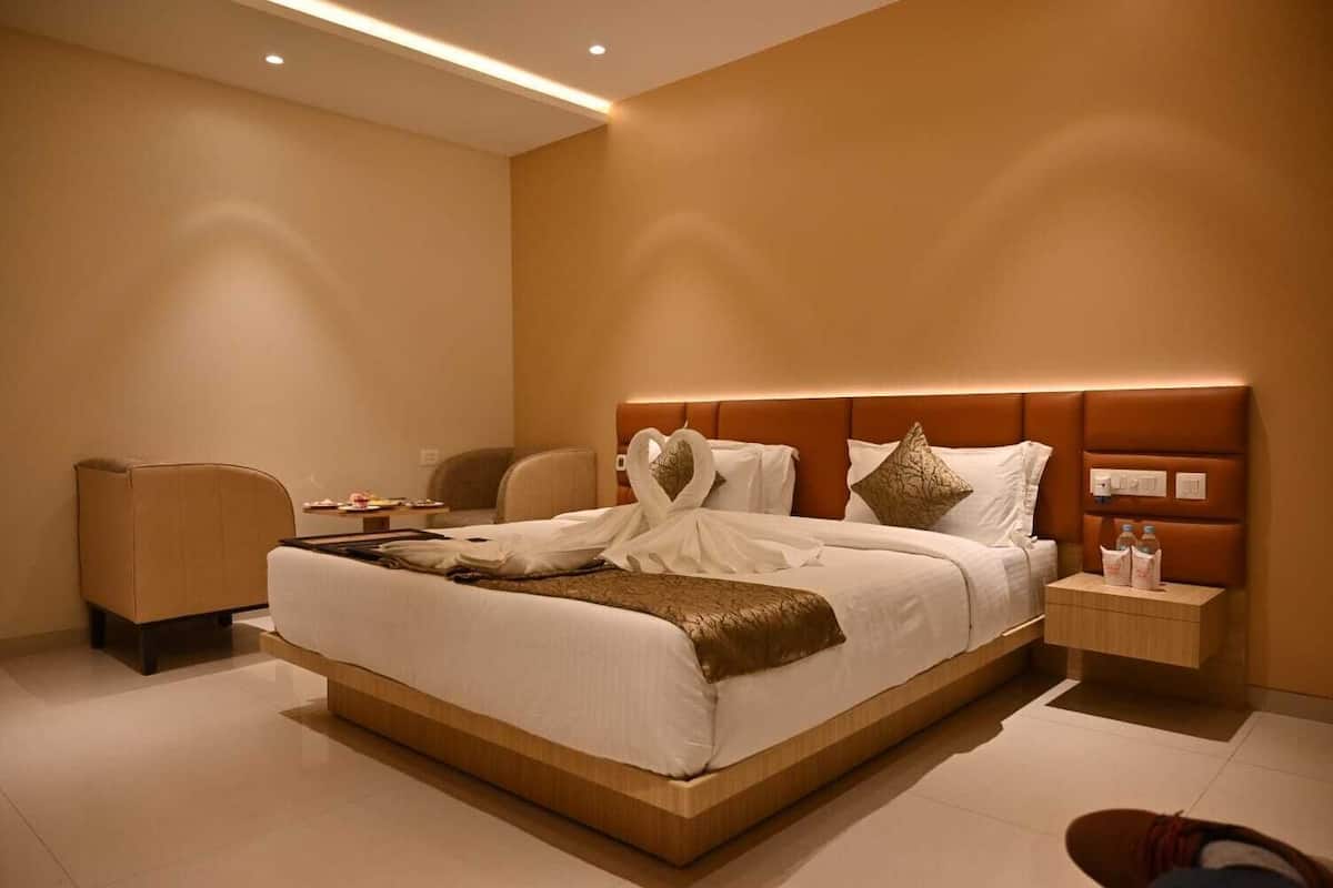 A hotel room with a large bed, a bedside table, a chair, and a nightstand.