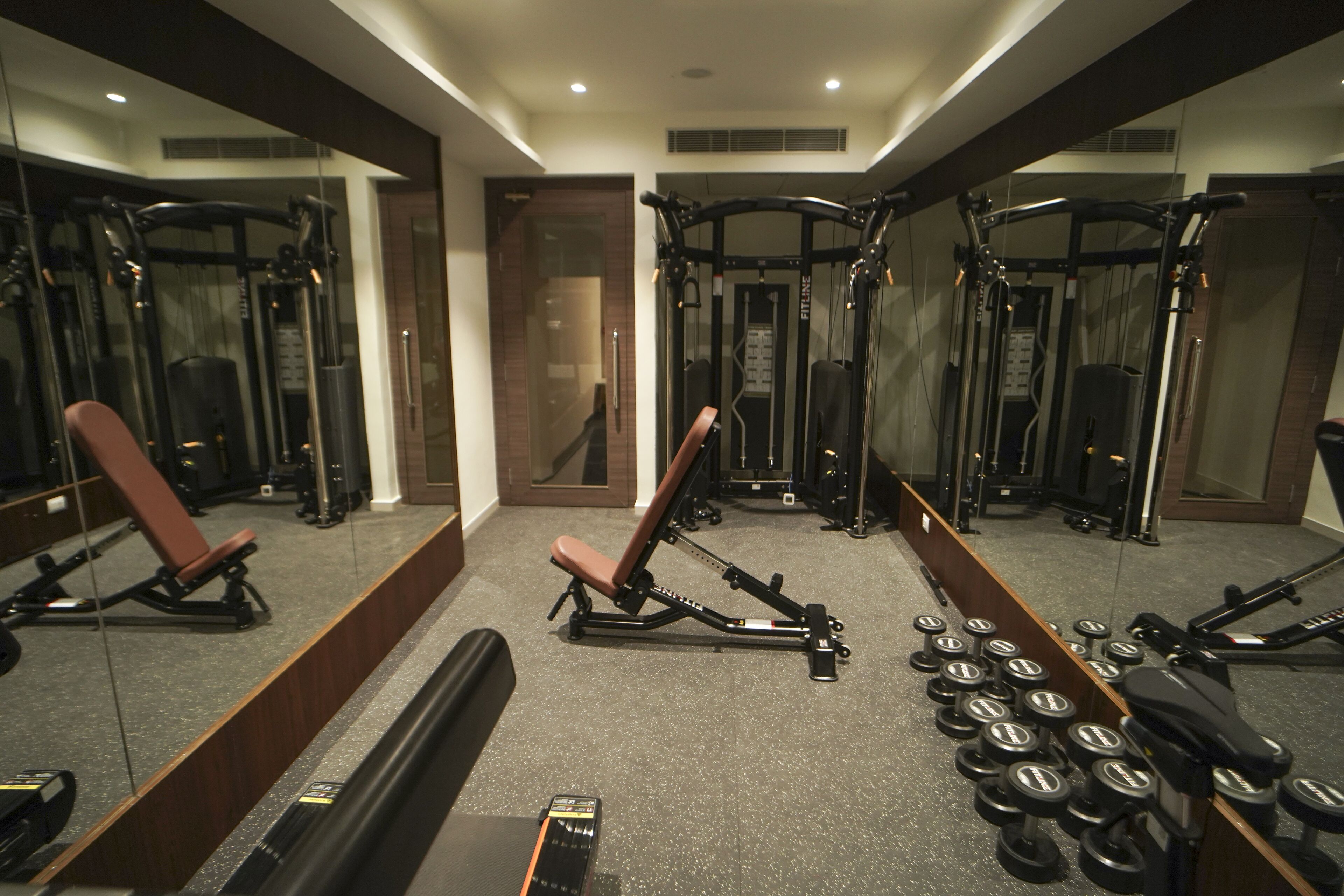 A gym with various exercise equipment, including benches, dumbbells, and weight machines.
