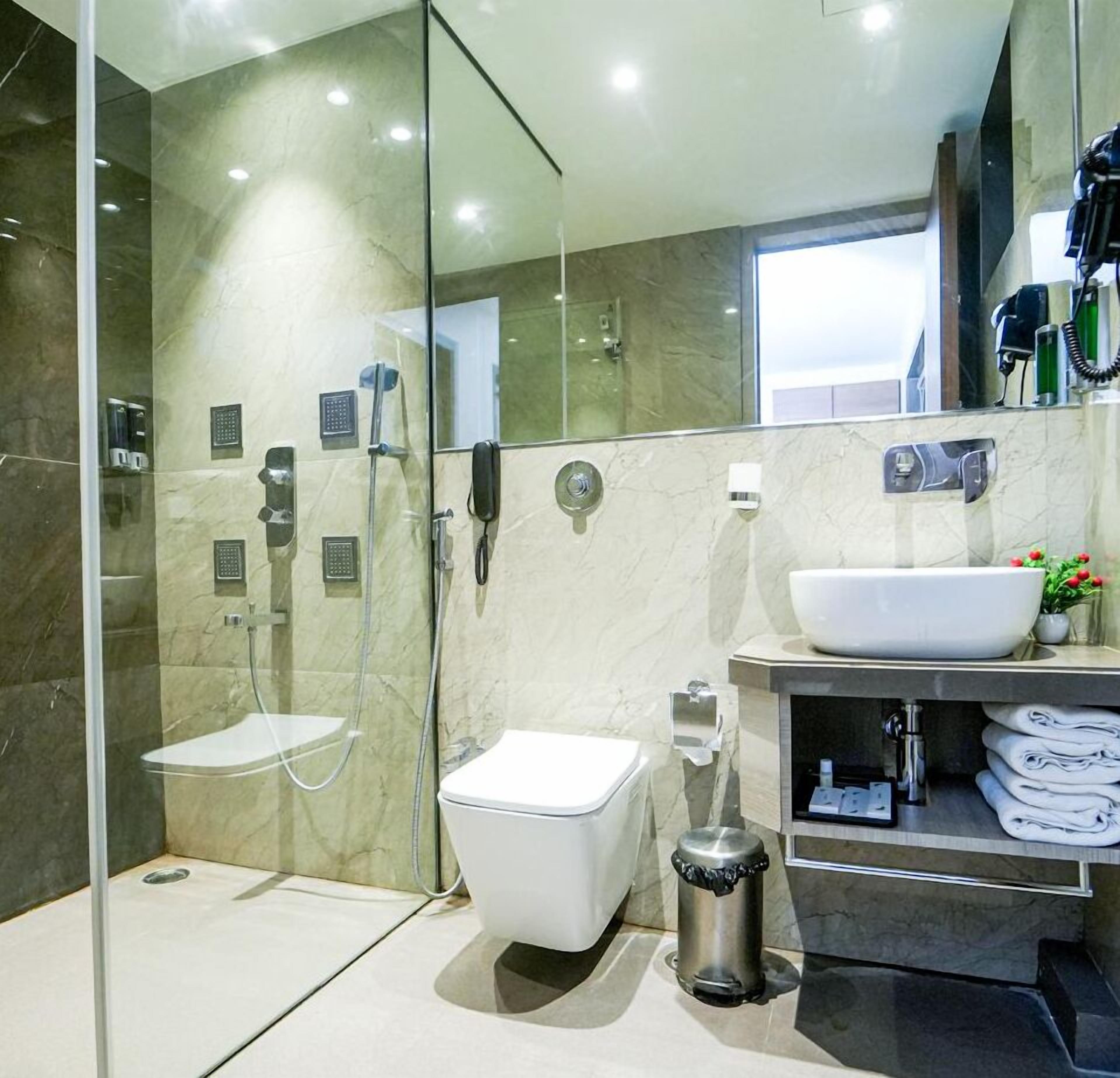 Une salle de bain moderne avec une douche à parois de verre, des toilettes, un lavabo et un meuble-lavabo avec des serviettes.