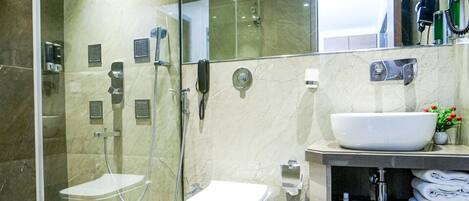 Une salle de bain moderne avec une douche à parois de verre, des toilettes, un lavabo et un meuble-lavabo avec des serviettes.