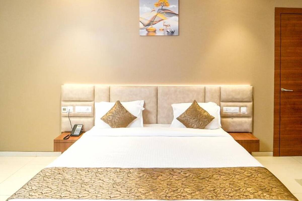 A hotel room with a large bed, a painting on the wall, and a wooden door.
