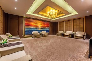 A spacious room with a large seating area, a staircase, and a wall with a sunset painting.