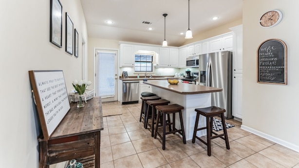 A modern kitchen with a central island, bar stools, a refrigerator, and a microwave. - Hotty Toddy get away in Oxford! (Oxford)