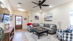 A living room with a gray sectional sofa, a black coffee table, a blue and white checkered armchair, and a ceiling fan. - Hotty Toddy get away in Oxford! (Oxford)