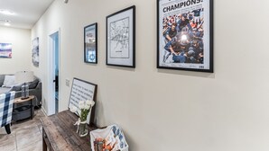 A hallway with framed pictures on the wall, a wooden table with a vase of flowers, and a framed inspirational quote. - Hotty Toddy get away in Oxford! (Oxford)