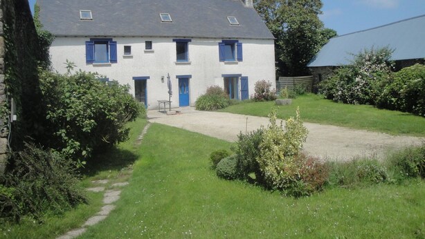 Ein zweistöckiges Haus mit Kiesauffahrt und Garten.
