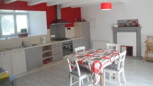 Eine moderne Küche mit weißen Schränken, einer roten Akzentwand, einem Gasherd und einem Essbereich mit Tisch und Stühlen.