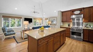 A spacious kitchen with wooden cabinets, a large island, and a stainless steel range hood. - Pelican Place - Golf cart included 704 Swordfish (Fripp Island)