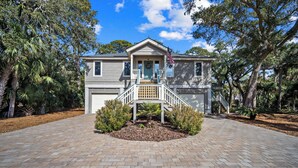A two-story house with a front porch, a garage, and a well-maintained driveway. - Pelican Place - Golf cart included 704 Swordfish (Fripp Island)