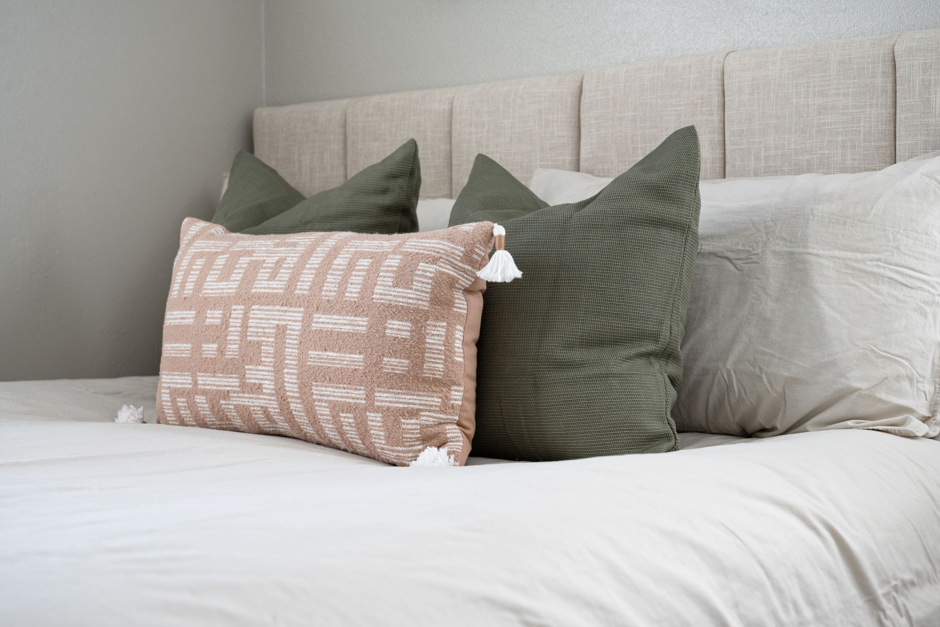 A bed with multiple pillows and a headboard.