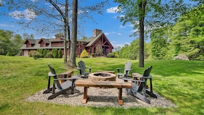 A rustic cabin with a stone fireplace, surrounded by a well-maintained lawn and trees.