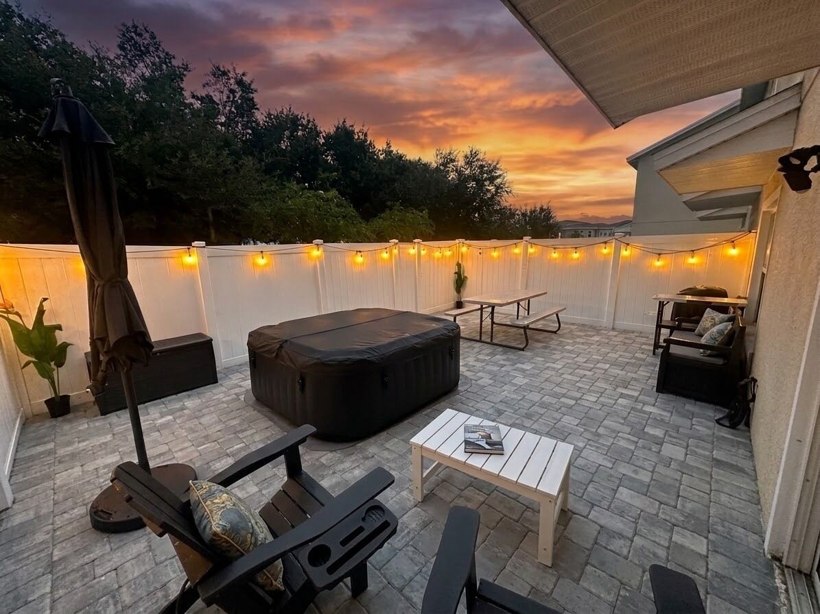 Een terras buiten met een zithoek, een tafel en sfeerverlichting.