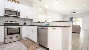 A modern kitchen with white cabinetry, stainless steel appliances, and pendant lighting.