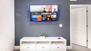 A flat-screen TV mounted on a gray wall with a white entertainment center below.