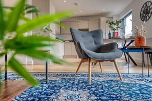 Relax in this stylish living room with a comfortable armchair, dining area, and large window.