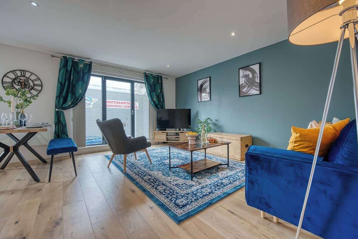 A living room with a sofa, a chair, a coffee table, a TV, and a window with curtains.