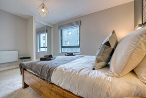 Relax in this cozy bedroom with a large bed and a window offering a view of the city.