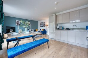 Enjoy a compact yet functional layout with a dining area, kitchen with ample counter space, and a cozy living area with a sofa and flat-screen TV.