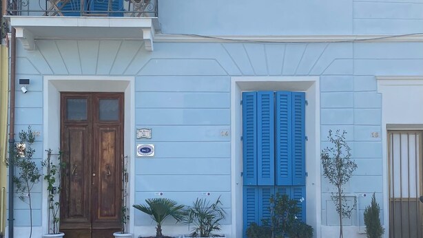 A two-story building with blue shutters, a wooden door, and potted plants. - Villa Valentina Versilia  (Viareggio)