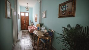 A hallway with a patterned floor, a pink sofa, a table with chairs, and a framed picture on the wall. - Villa Valentina Versilia  (Viareggio)