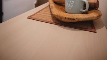 Una cocina con una mesa de madera, un rodillo y dos tazas con motivos de corazón.