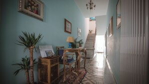 A hallway with a staircase, a wooden desk, a chair, a lamp, and two potted plants. - Villa Valentina Versilia  (Viareggio)