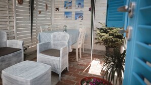 A patio area with wicker furniture, a table with a blue tablecloth, and a potted plant. - Villa Valentina Versilia  (Viareggio)