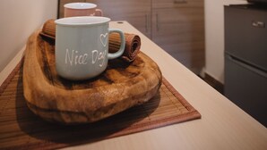 A kitchen with wooden cabinets, a coffee maker, and a tray with a mug and a bread roll. - Villa Valentina Versilia  (Viareggio)