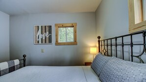 Ein Schlafzimmer mit einem Bett, einem Fenster an der Wand und einer Nachttischlampe.