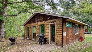 Eine Holzhütte mit einem Schild, auf dem "Osage" steht. Sie verfügt über eine Ziegelterrasse, einen Grill und eine Bank vor der Hütte.