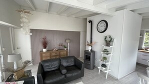 A modern living room with a black leather sofa, a wooden cabinet, a white coffee table, and a decorative plant. - Lake Garda Tignale vacation home bungalow with pool and lake view (Aer)