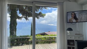 A room with a large sliding glass door leading to a balcony with a wooden deck. - Lake Garda Tignale vacation home bungalow with pool and lake view (Aer)