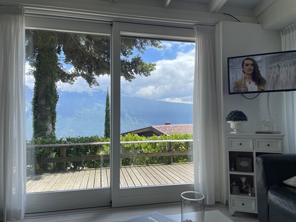 Ein Zimmer mit einer großen Glasschiebetür, die auf einen Balkon mit einer Holzterrasse führt.