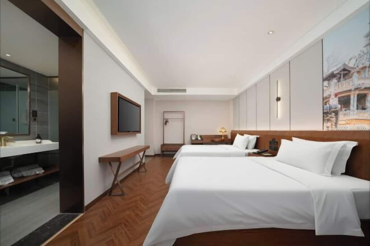 Ein Hotelzimmer mit zwei Betten, einem Schreibtisch, einem Fernseher und einem Badezimmer.