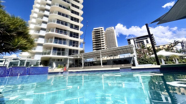 Un hôtel avec une piscine, des immeubles de grande hauteur et un ciel bleu dégagé.