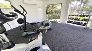 Une salle de sport équipée de machines de cardio, d’haltères et dotée d’un sol recouvert de moquette.