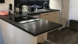 Una cocina moderna con encimera negra, electrodomésticos de acero inoxidable y armarios rojos.