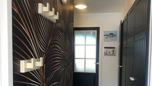 Un pasillo con una puerta oscura, una lámpara y una pared con un diseño geométrico.