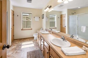 Un baño moderno con dos lavamanos, un espejo grande y una ducha.