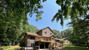 A two-story house with a front porch and a covered outdoor area. - Quiet relaxing wooded property. (New London)