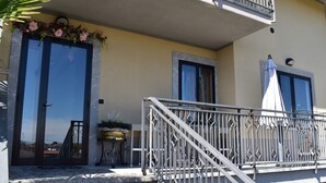 A balcony with a metal railing, a potted plant, and a door with a window. - Sundial One. Pradamano (Pradamano)